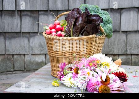 Un panier rempli de légumes frais et un bouquet sur une table rustique Banque D'Images