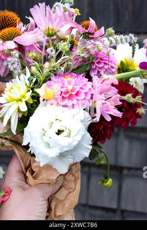 Main tenant un bouquet de fleurs en papier brun contre le mur rustique Banque D'Images