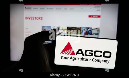 Personne tenant un smartphone avec le logo de la société américaine de machines agricoles AGCO Corporation devant le site Web. Concentrez-vous sur l'affichage du téléphone. Banque D'Images