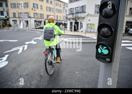 Tassin-la-demi-Lune (centre-est de la France), 2023/12/05 : cycliste portant un gilet jaune et un casque, traversant un feu vert, place de l'H. Banque D'Images