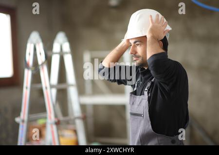 Ouvrier de la construction mettant le casque travaillant dans une maison en réforme Banque D'Images