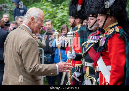 Le roi Charles III rencontre les membres de la bande du Royal Regiment of Scotland et les tuyaux et tambours du Royal corps of Signals après avoir inspecté la Balaklava Company, 5e bataillon, le Royal Regiment of Scotland, aux portes de Balmoral, comme il prend résidence d'été au château. Date de la photo : lundi 19 août 2024. Banque D'Images