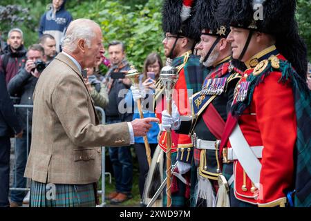 Le roi Charles III rencontre les membres de la bande du Royal Regiment of Scotland et les tuyaux et tambours du Royal corps of Signals après avoir inspecté la Balaklava Company, 5e bataillon, le Royal Regiment of Scotland, aux portes de Balmoral, comme il prend résidence d'été au château. Date de la photo : lundi 19 août 2024. Banque D'Images