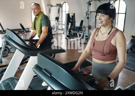 Les personnes qui s'exécutent sur des tapis roulants dans la salle de gym Banque D'Images