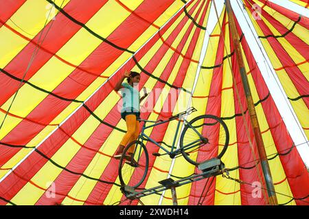 Sirajganj, Sirajganj, Bangladesh. 19 août 2024. Un membre de ''The New Lucky 7 Circus'' divertit le public en effectuant un numéro d'équilibre tout en se tenant debout sur un vélo à Sirajganj, au Bangladesh. Le cirque est une forme de divertissement populaire au Bangladesh qui est presque en train de disparaître. Une tradition de presque cent ans, ce jeu est montré dans une immense tente colorée. Ici, les artistes mettent en valeur leurs compétences à travers des cascades, acrobaties, clowns, marionnettes, marche serrée. (Crédit image : © Syed Mahabubul Kader/ZUMA Press Wire) USAGE ÉDITORIAL SEULEMENT! Non destiné à UN USAGE commercial ! Banque D'Images