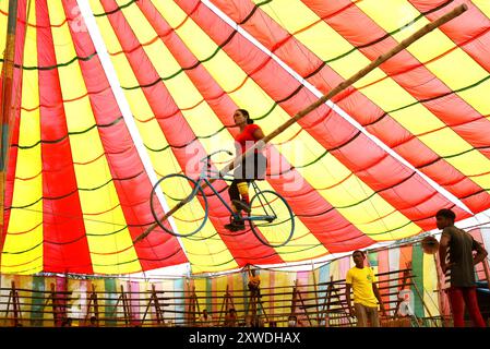 Sirajganj, Sirajganj, Bangladesh. 19 août 2024. Un membre de ''The New Lucky 7 Circus'' divertit le public en faisant du vélo sur une corde à 10 pieds au-dessus du sol à Sirajganj, au Bangladesh. Le cirque est une forme de divertissement populaire au Bangladesh qui est presque en train de disparaître. Une tradition de presque cent ans, ce jeu est montré dans une immense tente colorée. Ici, les artistes mettent en valeur leurs compétences à travers des cascades, acrobaties, clowns, marionnettes, marche serrée. (Crédit image : © Syed Mahabubul Kader/ZUMA Press Wire) USAGE ÉDITORIAL SEULEMENT! Non destiné à UN USAGE commercial ! Banque D'Images