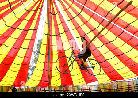 Sirajganj, Sirajganj, Bangladesh. 19 août 2024. Un membre de ''The New Lucky 7 Circus'' divertit le public en faisant du vélo sur une corde à 10 pieds au-dessus du sol à Sirajganj, au Bangladesh. Le cirque est une forme de divertissement populaire au Bangladesh qui est presque en train de disparaître. Une tradition de presque cent ans, ce jeu est montré dans une immense tente colorée. Ici, les artistes mettent en valeur leurs compétences à travers des cascades, acrobaties, clowns, marionnettes, marche serrée. (Crédit image : © Syed Mahabubul Kader/ZUMA Press Wire) USAGE ÉDITORIAL SEULEMENT! Non destiné à UN USAGE commercial ! Banque D'Images