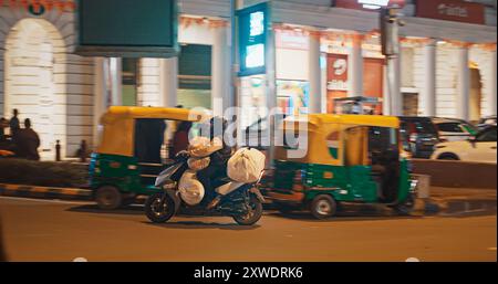 New Delhi, Delhi, Inde. L'homme indien transporte une cargaison chargée sur un vélo. Trafic sur la rue Connaught Lane dans la nuit. Banque D'Images