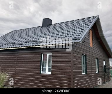 Toit de maison rapproché avec tôle de toiture en acier. Panneau de toiture modulaire sombre à effet de tuile. Carreaux de bardeaux métalliques traditionnels. Profilé métallique ondulé Banque D'Images