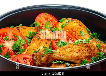 Cuisses de poulet frites dans une poêle. Cuisses de poulet frites prêtes à manger avec tomates et légumes verts. Banque D'Images