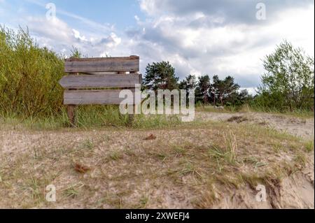 Un panneau de signalisation se dresse au milieu de hautes herbes et de sable, guidant les visiteurs dans la nature. Maquette Banque D'Images