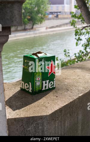 Paris, France 08.19.24. Emballage en carton d'un paquet de 6 bouteilles de bière Heineken laissé sur un mur le long des berges de la Seine, Paris Banque D'Images