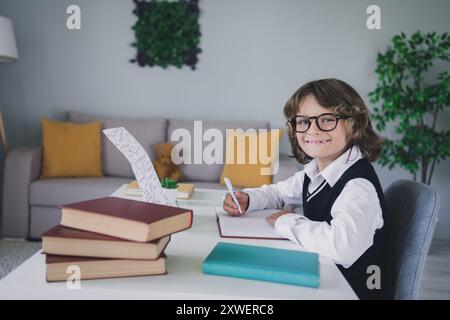 Portrait de charmant garçon intelligent et joyeux étudiant de la maison faisant Hometask intérieur de la chambre moderne à l'intérieur Banque D'Images