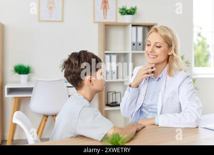 Dentiste pédiatrique montrant de bonnes dents blanches saines au petit garçon, expliquant les règles d'hygiène bucco-dentaire. Banque D'Images