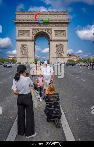Paris, France - 08 19 2024 : Jeux Olympiques Paris 2024. Vue de l'Arc de Triomphe avec le symbole des jeux paralympiques et des touristes en face Banque D'Images