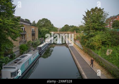 Regents canal et chemin de halage dans le nord de Londres regardant vers l'ouest depuis le large pont de promenade par un matin d'été calme, le 19 août 2024 Banque D'Images