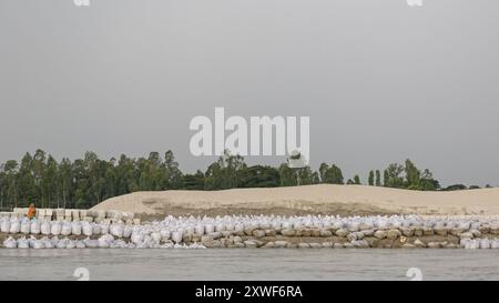 Des barrières anti-inondation et des digues construites avec d'énormes sacs de sable et des dalles de béton protégeront une partie du ghat de Gaibandha des énormes forces de la rivière Brahmapoutre - pour l'instant. Les personnes vivant dans les chars - des îles sédimentaires temporaires dans les grands fleuves du Bangladesh - sont particulièrement vulnérables aux phénomènes météorologiques causés par le changement climatique. L'ONG Friendship a divers programmes de sensibilisation pour aider à atténuer les impacts. Banque D'Images