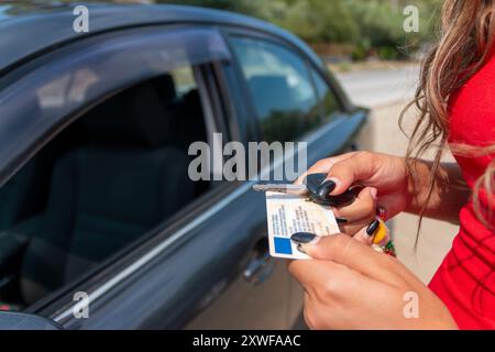 Adolescente montrant son permis de conduire dans la fenêtre de la voiture après avoir réussi l'examen Banque D'Images