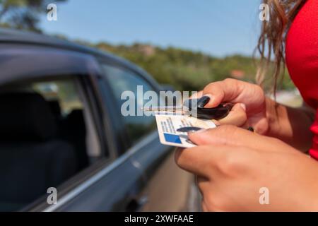 Adolescente montrant son permis de conduire dans la fenêtre de la voiture après avoir réussi l'examen Banque D'Images