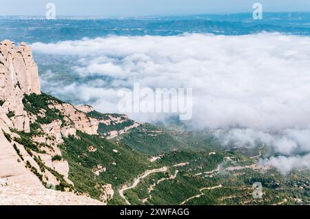 Vue depuis le pic Sant Jeroni des montagnes de Montserrat et des nuages sur le paysage verdoyant Banque D'Images