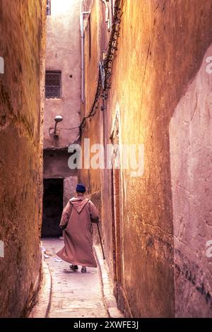 Fès, Maroc - 19 mars 2024 : vieil homme en vêtements traditionnels dans les rues étroites du vieux souk de la médina de Fès, Maroc. Banque D'Images