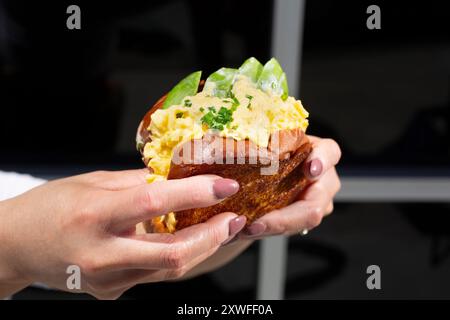 Une vue des mains tenant un oeuf d'avocat sando. Banque D'Images