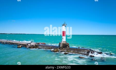 Vue aérienne du phare rouge et blanc sur Breakwater dans les eaux turquoise Banque D'Images