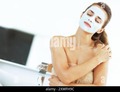 jeune femme avec masque cosmétique facial dans la salle de bain Banque D'Images