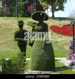 Figure topiaire verte extérieure de femme dans la robe longue de style ancien dans le parc Banque D'Images