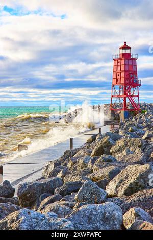 Vibrant phare rouge sur Rocky Shoreline avec des vagues qui s'écrasent à hauteur des yeux Banque D'Images