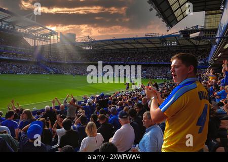 Chelsea, Londres, Royaume-Uni 18 août, 2024 le premier match de la premier League pour Chelsea Football Club et les champions de Manchester City Football Club l'année dernière ont joué à Stamford Bridge. Notre photo montre : (OPS) : les fans de Chelsea tentent de rallier leurs joueurs alors que le soleil se couche sur le stade Banque D'Images