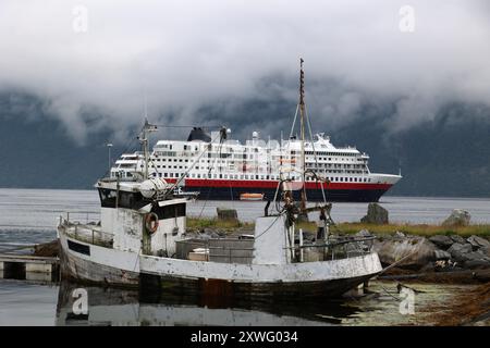 Vieux bateau de pêche avec bateau de croisière moderne en arrière-plan dans le Hjorundfjord dans le port de la petite communauté Saebo, Norvège Banque D'Images