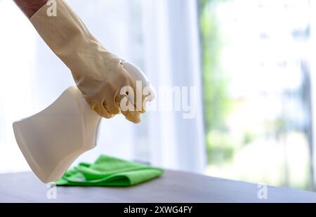 homme en gants de protection jaunes saupoudrant avec un agent nettoyant. nettoyage dans l'appartement ou la chambre d'hôtel Banque D'Images