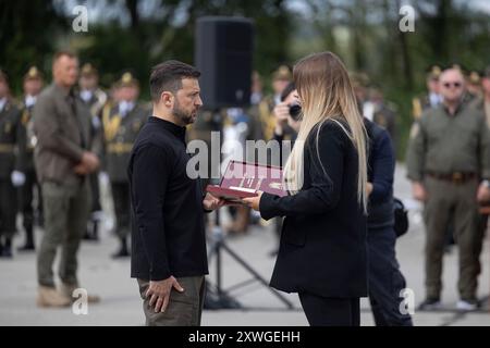 Kiev, Ukraine. 04 août 2024. Le président ukrainien Volodymyr Zelenskyy, à gauche, présente l'ordre de l'étoile d'or à l'épouse du héros déchu de l'Ukraine, le lieutenant-colonel Denys Vasyliuk, lors d'une célébration de la Journée de l'Armée de l'Air, le 4 août 2024 dans un lieu inconnu en Ukraine. Au cours de l'événement, Zelenskyy a dévoilé le premier groupe d'avions Lockheed Martin F-16 Fighting Falcon. Crédit : Présidence ukrainienne/Bureau de presse présidentiel ukrainien/Alamy Live News Banque D'Images