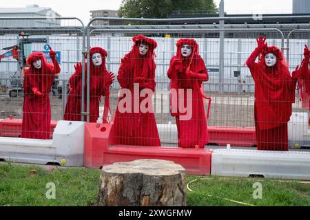 Londres, Royaume-Uni. 19 août 2024. La troupe de mime, militante des Red Rebel d'extinction Rebellion, se produit autour de la gare Euston dans une manifestation silencieuse contre les impacts environnementaux du projet ferroviaire HS2, y compris la perte d'arbres et d'espaces verts. Le projet, dont l'avenir est incertain, a dépassé largement le budget et a provoqué des bouleversements massifs dans la région, y compris la perte de maisons, d'entreprises et l'exhumation de 50 000 restes humains. Crédit : Ron Fassbender/Alamy Live News Banque D'Images