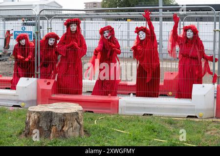 Londres, Royaume-Uni. 19 août 2024. La troupe de mime, militante des Red Rebel d'extinction Rebellion, se produit autour de la gare Euston dans une manifestation silencieuse contre les impacts environnementaux du projet ferroviaire HS2, y compris la perte d'arbres et d'espaces verts. Le projet, dont l'avenir est incertain, a dépassé largement le budget et a provoqué des bouleversements massifs dans la région, y compris la perte de maisons, d'entreprises et l'exhumation de 50 000 restes humains. Crédit : Ron Fassbender/Alamy Live News Banque D'Images