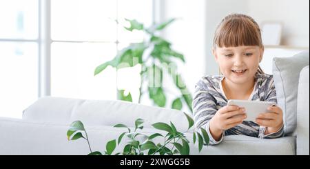 Petite fille avec téléphone mobile à la maison Banque D'Images