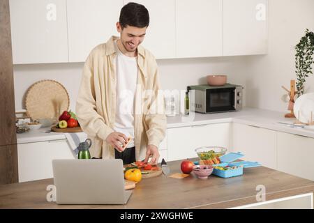 Jeune homme faisant sandwich pour boîte à lunch dans la cuisine Banque D'Images