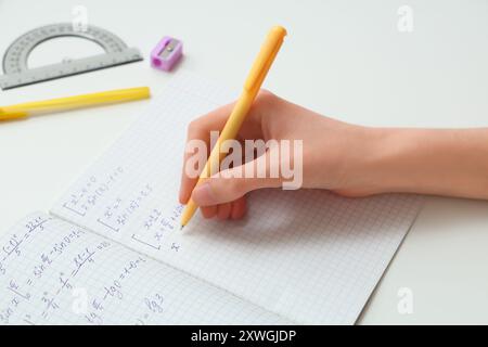 Femme écrivant des formules mathématiques dans copybook sur la table lumineuse, gros plan Banque D'Images