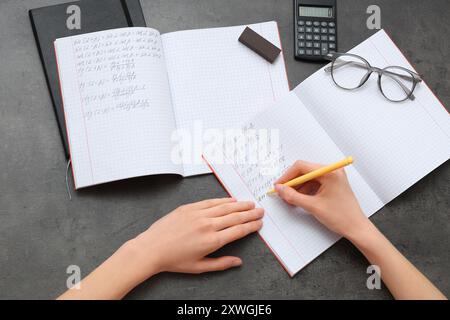 Femme écrivant des formules mathématiques sur fond sombre Banque D'Images