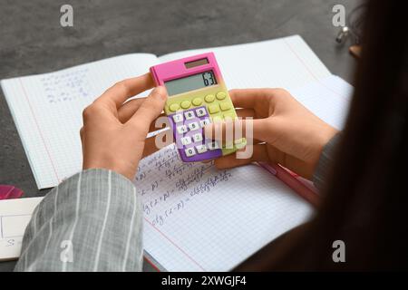 Femme travaillant avec la calculatrice à la table, gros plan Banque D'Images