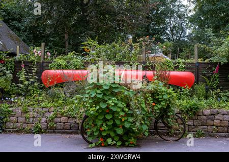 Canoë rouge et vélo envahi de lierre dans le quartier de Freetown Christiania à Copenhague Banque D'Images