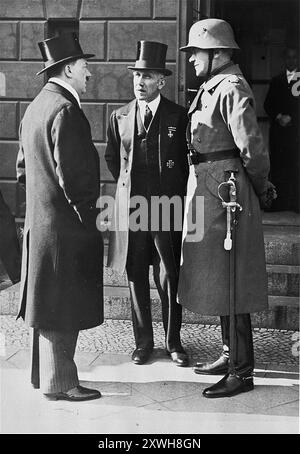 Le chancelier Adolf Hitler, le vice-chancelier von Papen et le ministre de la Défense von Blomberg attendent devant l'opéra le président du Reichs le jour de deuil national allemand. Cet événement a eu lieu juste après la nomination d'Hitler comme chancelier. Dans l'un des masterstrokes d'Hitler, il se tenait devant von Hindenberg alors qu'il quittait l'événement et, la tête inclinée, serrait révéremment sa main. La photo qui en résulte a beaucoup contribué à créer l'illusion que Hindenburg approuvait Hitler, ce qui n'était pas vrai, et que Hitler respectait le président vieillissant, ce qui n'était pas non plus vrai. La photo est datée du 1933 mars 12. Banque D'Images