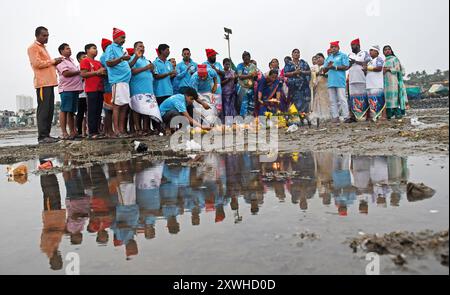 Mumbai, Inde. 19 août 2024. Les gens de la communauté de pêcheurs effectuent des rituels pendant la célébration de 'Narali Poornima' (jour de la noix de coco) sur la plage de Mumbai. Les membres de la communauté de pêcheurs hindoue dans la région côtière de l'État du Maharashtra effectuent des rituels près de la mer en offrant des noix de coco et en priant pour une saison de pêche sûre à venir. Crédit : SOPA images Limited/Alamy Live News Banque D'Images