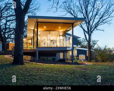 Ajout moderne à la maison avec pont surélevé vu avec des lumières allumées au crépuscule Banque D'Images