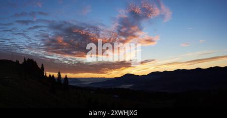 Le coucher de soleil à couper le souffle peint le ciel avec des teintes vibrantes de rose, orange, violet, se fondant dans le ciel bleu du matin. Les montagnes aux silhouettes et les pins créent une toile de fond sereine. Paysage tranquille et pittoresque. Banque D'Images