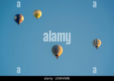 Montgolfières en bleu foncé, rouge et jaune volant dans un ciel bleu légèrement nuageux Banque D'Images