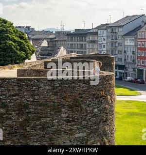 Femme touristique regardant au-dessus de la muraille romaine de Lugo et contemplant la ville du haut du monument, la Galice. Banque D'Images