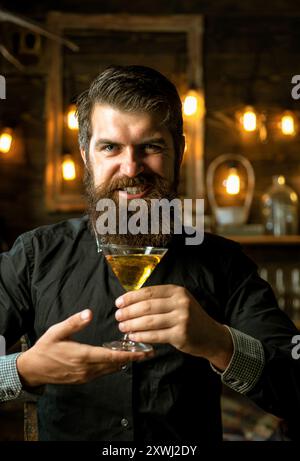 Homme attrayant avec un verre de martini dans ses mains. Alcoolisme. Banque D'Images