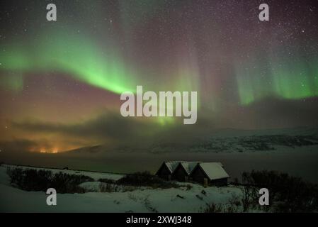 Aurores boréales au-dessus des cabanes près de Olderfjord, sur le chemin de Nordkapp (Cap Nord) (Finnmark, Norvège) ESP : auroras boreales sobre unas Cabañas Banque D'Images